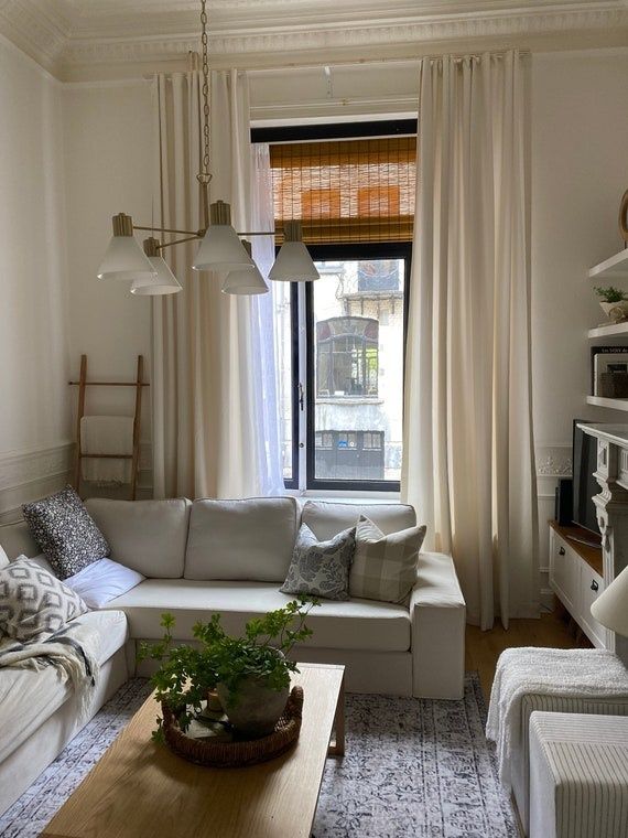 Ljust vardagsrum med gardiner, soffa och mjuka textilier